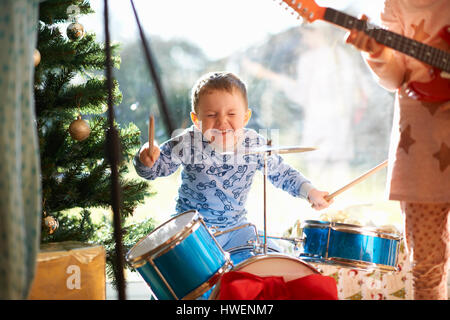 Boy and sister playing toy drum kit and guitar on christmas day Stock Photo