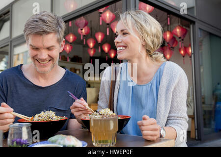 Couple eating noodles at city sidewalk cafe Stock Photo