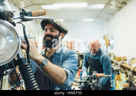 Two mature men, working on motorcycle in garage Stock Photo
