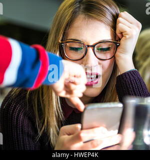 Young woman with boy's hand pointing at smartphone in cafe Stock Photo