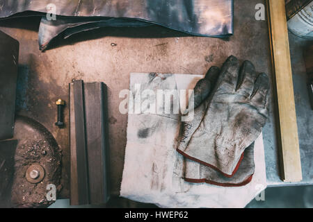 Overhead view of metals and protective gloves on forge workbench Stock Photo
