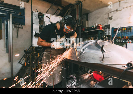 Metalworker grinding metal in forge workshop Stock Photo
