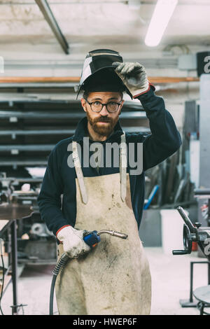 Portrait of metalworker holding welding torch in forge workshop Stock Photo