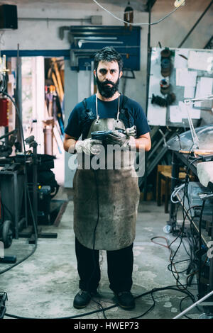 Portrait of male metalworker in apron, forge workshop Stock Photo
