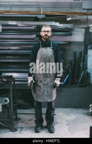Portrait of male metalworker in apron, forge storeroom Stock Photo