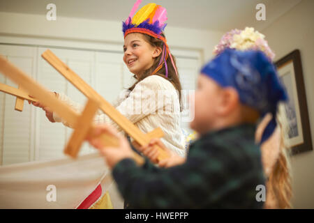 Dressed up boy and two sisters having sword fight Stock Photo