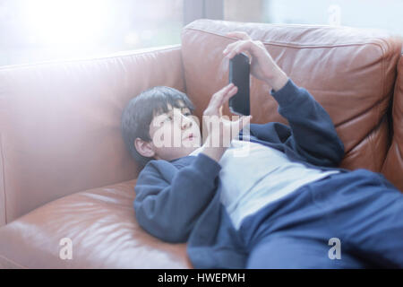 Boy playing with smartphone on sofa Stock Photo