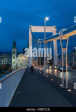 A woman walking across the Erzsebet / Elisabeth Bridge in Budapest, Hungary at blue hour Stock Photo