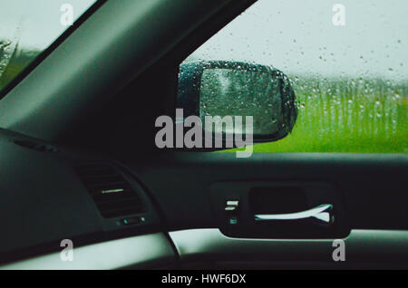 There are raindrops on the passenger window. The photo is taken in the front panel on the passenger side. it's during a rain storm. Stock Photo