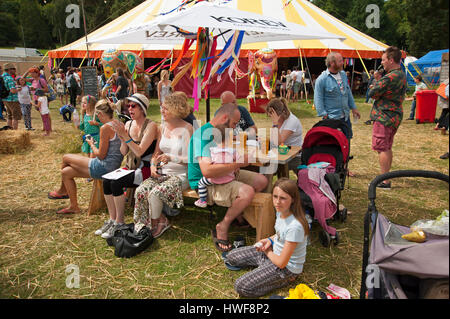 Families sitting at a table under a parasol enjoying the beer at the Port Eliot Festival Cornwall Stock Photo