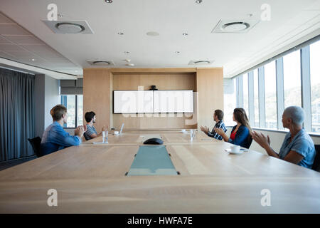 Creative business team applauding while attending a conference call in office Stock Photo