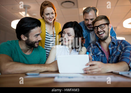 Happy creative business team discussing over digital tablet in office Stock Photo