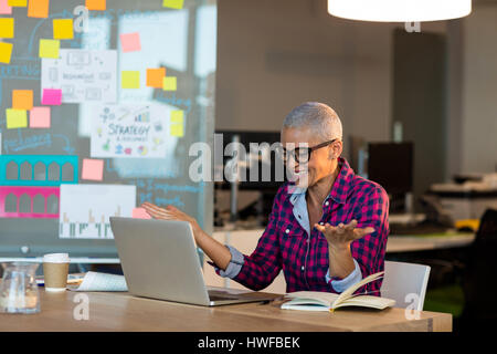 Overjoyed  creative businesswoman sitting on desk at office Stock Photo