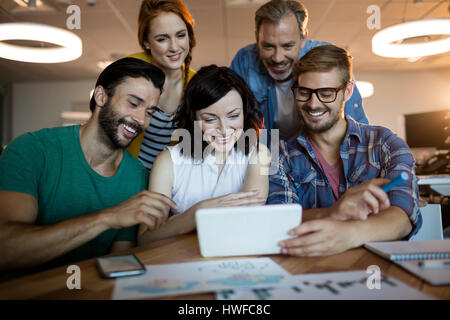Happy creative business team discussing over digital tablet in office Stock Photo