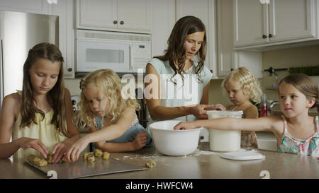 Mother and daughters baking cookies together in kitchen Stock Photo