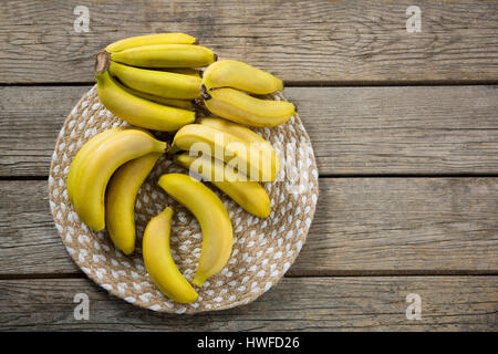 Overhead of fresh bunch of bananas in plate on wooden table Stock Photo