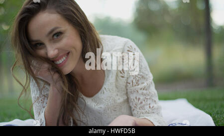 Close up portrait of smiling woman laying in grass Stock Photo