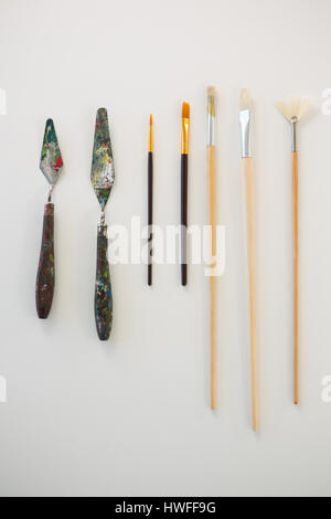 Palette knives and paint brushes arranged in a row on white background Stock Photo