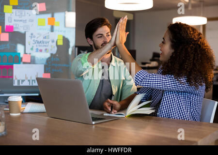 Creative business people giving high five to each other at desk in office Stock Photo
