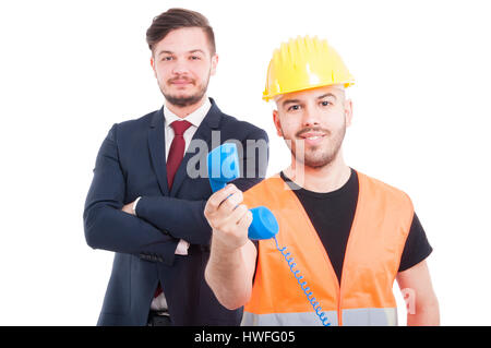 Happy young builder holding phone receiver and smiling near businessman isolated on white Stock Photo