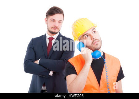 Constructor or engineer calling somebody while businessman standing with folded arms behind him isolated on white Stock Photo