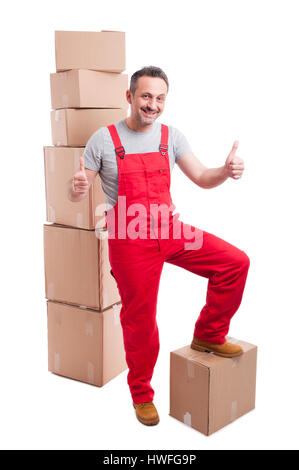 Smiling mover man showing like gesture with both hands standing around boxes looking trustworthy isolated on white background Stock Photo