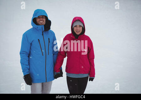 Smiling couple standing in snowy forest Stock Photo