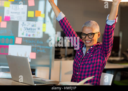 Creative businesswoman celebrating on desk at office Stock Photo