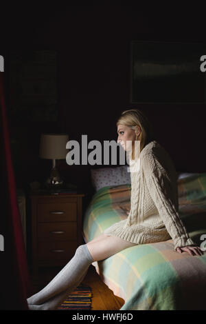 Woman sitting on bed in bedroom Stock Photo