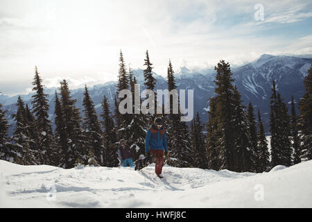 Men running on snow covered mountain against trees Stock Photo