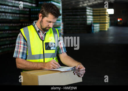 Confident male worker writing on clipboard in warehouse Stock Photo