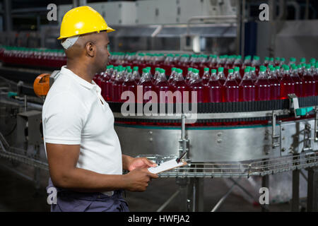 Side view of male worker inspecting bottles in juice factory Stock Photo