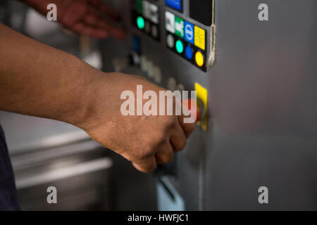 Cropped hand of male worker operating machinery in factory Stock Photo
