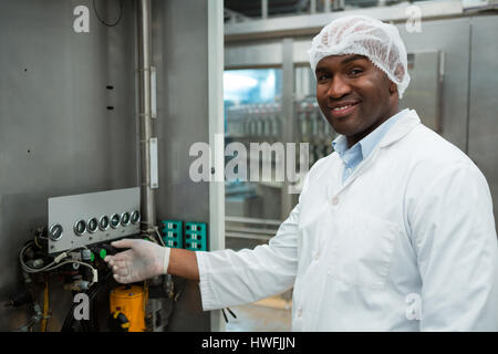 Portrait of confident male worker operating machine in juice factory Stock Photo