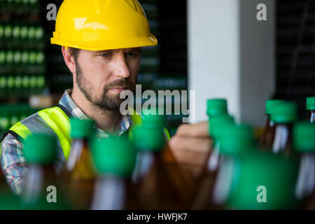 Serious man examining juice bottles in factory Stock Photo
