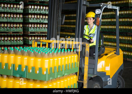 Confident female worker driving forklift in distribution warehouse Stock Photo