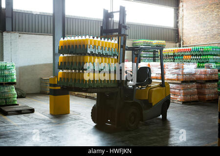 Stack of packed juice bottles and forklift in distribution warehouse Stock Photo