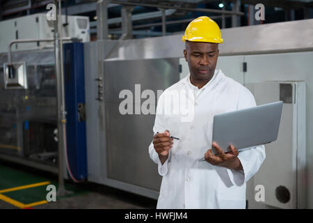 Serious male worker using laptop in manufacturing industry Stock Photo