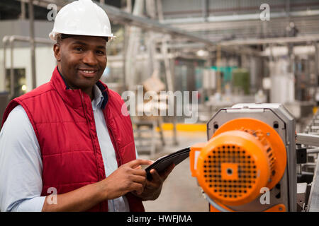 Happy male employee using digital tablet in juice factory Stock Photo