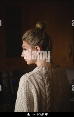 Thoughtful woman in kitchen at home Stock Photo