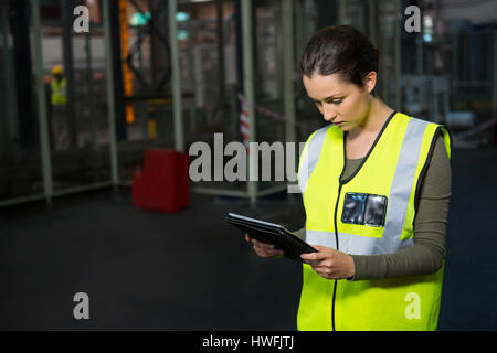 Confident female worker using tablet pc in warehouse Stock Photo