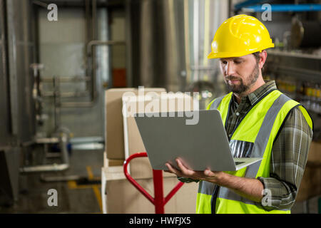 Serious male worker using laptop in distribution warehouse Stock Photo