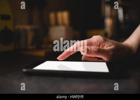 Womans hand using digital tablet in the kitchen at home Stock Photo