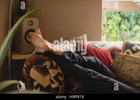 Woman lying on couch in living room at home Stock Photo