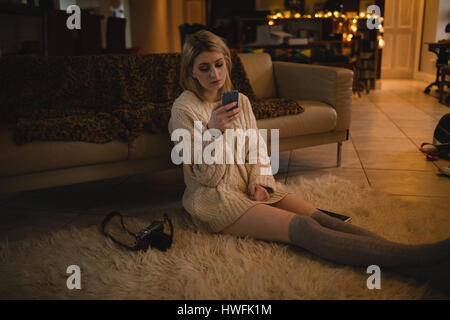 Woman using mobile phone while sitting at home Stock Photo