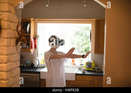 Woman gesturing while using virtual reality headset at home Stock Photo