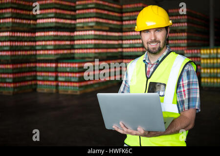 Portrait of young male worker using laptop in warehouse Stock Photo