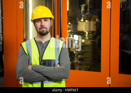 Portrait of confident male worker standing against door at factory Stock Photo