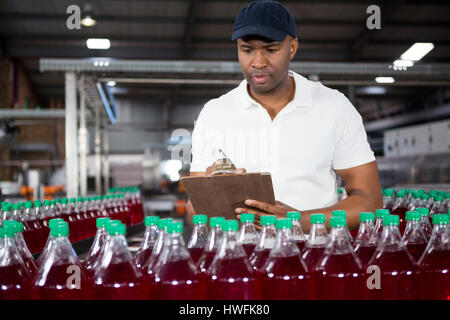 Confident male worker writing on clipboard in factory Stock Photo