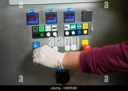 Cropped hand of manual worker operating machine in factory Stock Photo